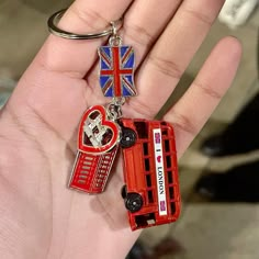 a hand holding a red bus with a british flag on it and a heart shaped keychain