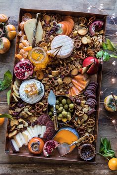 an assortment of cheeses, fruits and crackers in a wooden box on a table