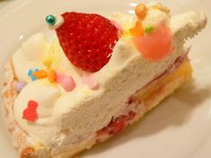 a piece of cake with white frosting and strawberries on top is sitting on a plate