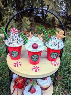 three red cups filled with whipped cream and candy canes on top of a table