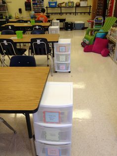 an empty classroom with desks, chairs and bins on the floor in front of them