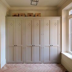 an empty room with many white cupboards and a light fixture hanging from the ceiling