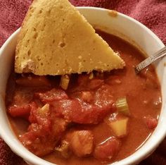 a white bowl filled with chili and tortilla chips on top of a pink towel