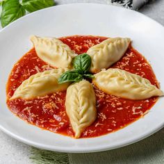 three dumplings in tomato sauce on a white plate