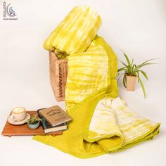 a yellow blanket sitting on top of a wooden table next to a potted plant