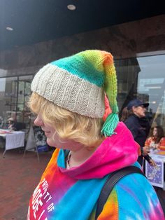 a woman wearing a tie dye hat and colorful scarf on her head while standing in front of a building