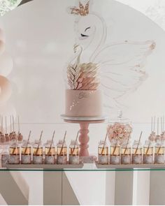 a table topped with a pink cake and lots of desserts on top of it