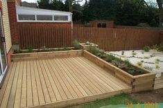 a wooden deck in front of a house with plants growing out of the bottom half