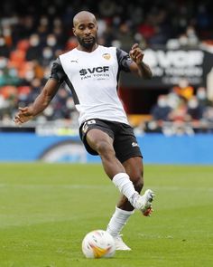 a man kicking a soccer ball on top of a field