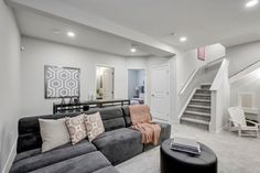 a living room filled with furniture next to a stair case and white walls in the background