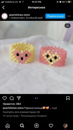 two pink and yellow beaded earrings on top of a white sheet with black eyes