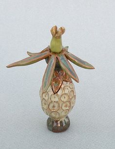 a ceramic figurine with a flower in it's center on a white surface