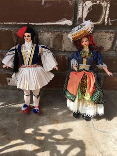 two dolls are standing next to each other in front of a brick wall and shadow