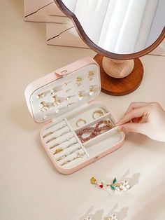 a person is holding an open jewelry box on a table with other items in it