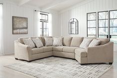 a living room with a sectional couch and rug in front of large windows on the wall