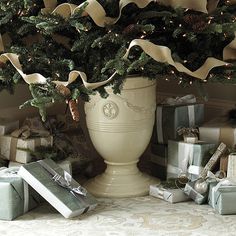 a large white vase filled with presents under a christmas tree