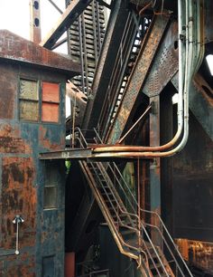 an old rusted metal structure with stairs leading up to the top and bottom floor