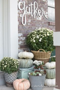 the front porch is decorated with white pumpkins and flowers