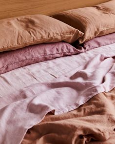 an unmade bed with pink and brown sheets