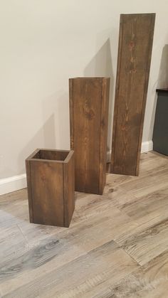 three wooden boxes sitting on top of a hard wood floor next to a white wall