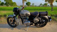 the motorcycle is parked on the side of the road in front of some green grass