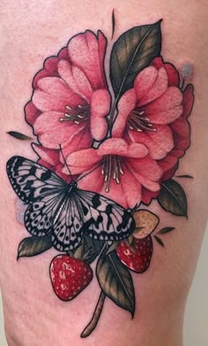 a woman's thigh with flowers and butterflies on it, while she is showing off her tattoo