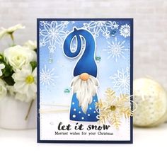 a christmas card with a gnome and snowflakes on the table next to some flowers