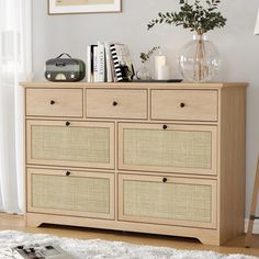 a wooden dresser with baskets on top of it next to a white rug and window