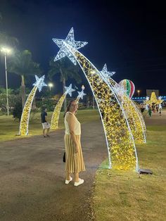 a woman is standing in front of some christmas lights