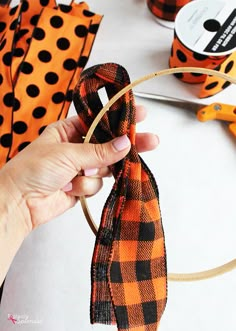 a person is holding a ribbon in front of some orange and black polka dot ribbons