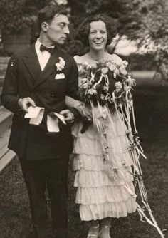 an old black and white photo of a man and woman in formal wear holding flowers