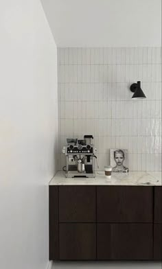 a coffee machine sitting on top of a counter next to a wall mounted faucet