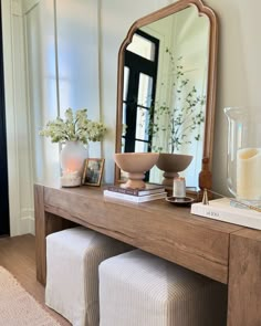 a wooden table topped with a mirror next to a vase filled with flowers and candles