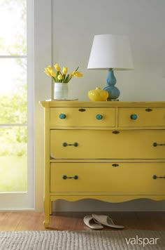 a yellow dresser with flowers and shoes on top