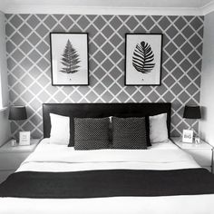 a black and white bedroom with two pictures on the wall above the bed, along with pillows