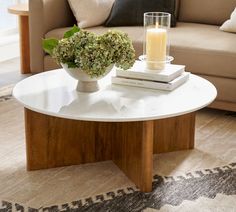 a coffee table with a candle and some books on it in a living room area