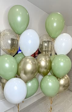 a bunch of balloons that are in front of a mirror on the wall with some gold and white balloons