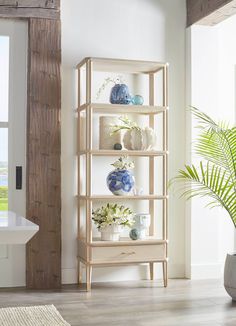 a shelf filled with vases and flowers next to a potted palm tree in a living room