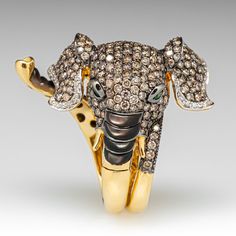 This stunningly crafted 18k yellow gold and black rhodium ring features an elephant wrap design that is pavé set with two-hundred sixty-three (263) round brilliant cut champagne diamonds. The ears are lined with a total of sixty-one (61) bead set round brilliant cut diamonds. The eyes are each channel set with one (1) round modified brilliant cut tsavorite garnet. The top and bottom of the trunk is accented with black Mother-of-pearl carvings. The ring measures 36.4mm at the top, rises 12.6mm ab Elephant Rings, Rhodium Ring, Black Rhodium Ring, Elephant Ring, Treasure Jewelry, Tsavorite Garnet, Bead Set, An Elephant, Champagne Diamond