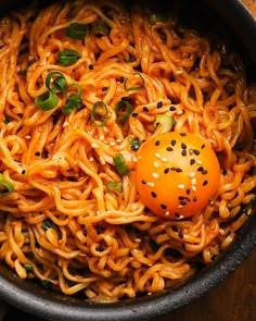 a bowl filled with noodles and an egg on top of it, sitting on a wooden table