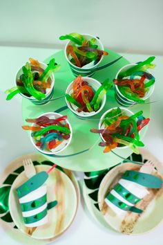 a table topped with paper plates and bowls filled with gummy bears sitting on top of each other