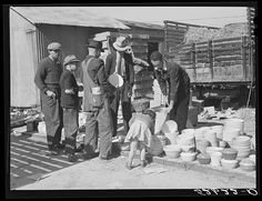 an old black and white photo of men working in a yard with buckets on the ground