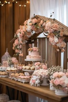 a table filled with cakes and cupcakes on top of wooden tables covered in pink flowers