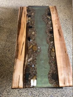 a table made out of wood and glass with rocks on the bottom, water running through it