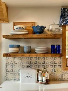 the shelves above the kitchen sink are made out of wood and have dishes on them