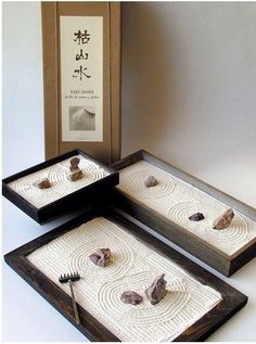 three wooden trays with rocks in them and a box on the ground behind them