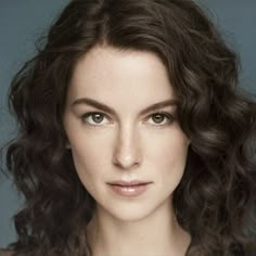 a close up of a woman with curly hair and blue eyes wearing a black dress