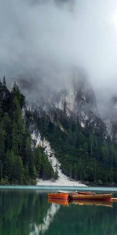 two canoes sitting on the water in front of a mountain