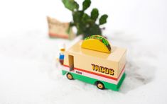 a toy taco truck is sitting in the snow next to a potted plant