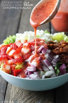 strawberry salsa being poured into a bowl with chopped salad